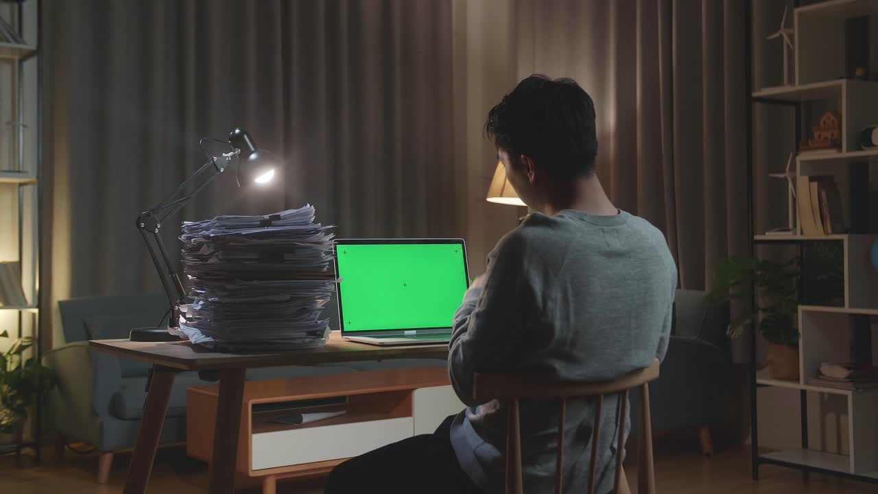 집 에서 문서 를 작업 하는 동안 녹색 스크린 노트북 과 대화 하는 아시아인 의 뒷면