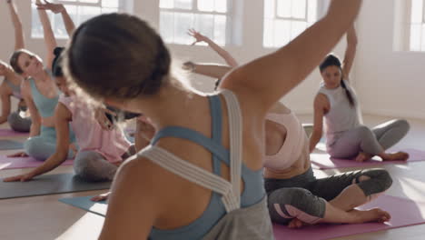 yoga class of beautiful women practice seated side bend pose enjoying healthy lifestyle exercising in fitness studio instructor teaching group meditation at sunrise