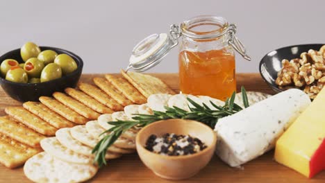 bowl of green olives, spices, crispy biscuits, jam, rosemary herb, cheese and walnuts