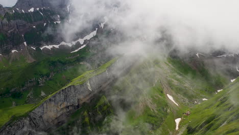 Downward-angle-drone-shot-of-Altenalp-Turm,-with-clouds-covering-the-mountainside