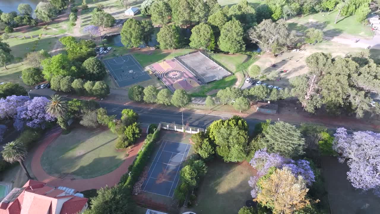A park with tennis courts, trees, and a quiet suburban atmosphere in northern sandton, aerial view