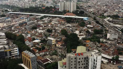 Toma-Aérea-De-Arriba-Hacia-Abajo-Del-Distrito-De-Tugurios-De-La-Ciudad-De-Yakarta-Y-El-Tráfico-En-La-Autopista