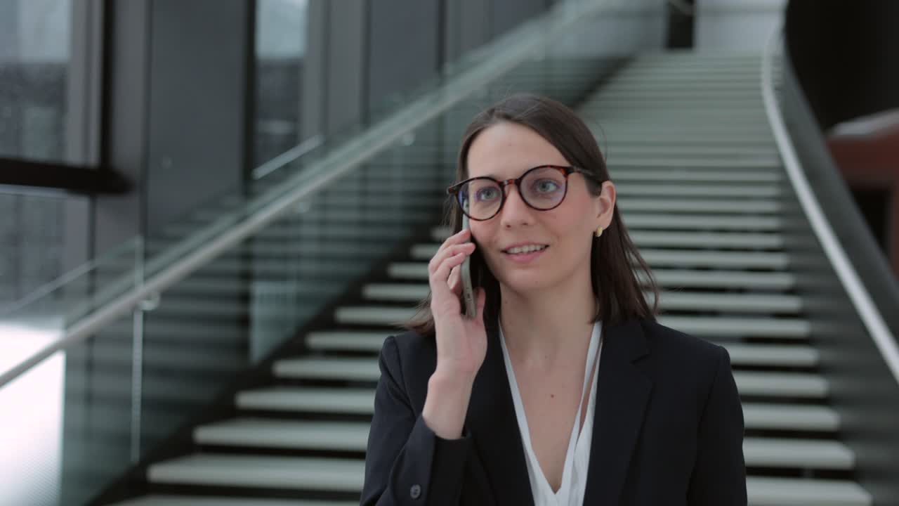 mujer de negocios con un traje de negocios con una maleta camina por el aeropuerto o el centro de negocios y habla por teléfono. una mujer europea confiada