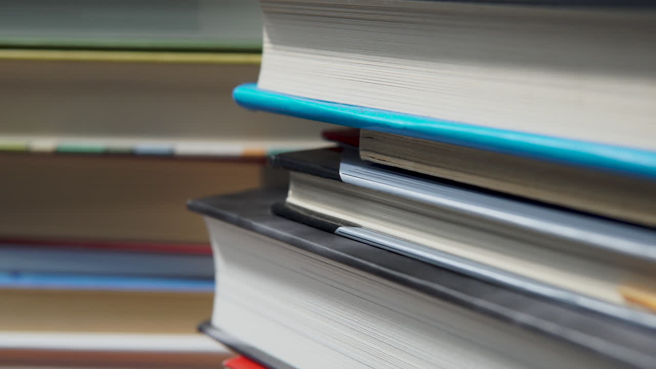 Close up view of stacked books - shallow depth soft focus pan shot
