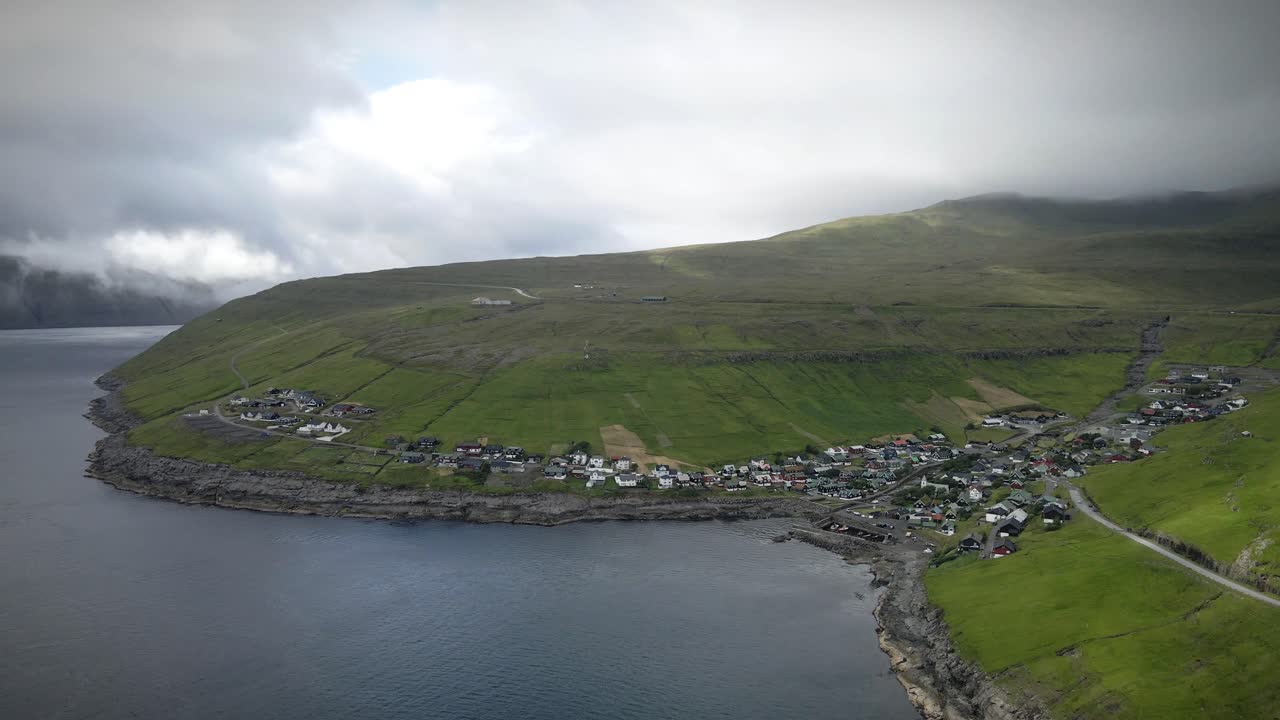 스트레이모이 섬의 거친 해안선에 있는 화려한 마을인 비비크 (kvívík) 는 구름이 가득한 하늘 아래 다채로운 집과 초록색 과 눈에 띄는 산들로 가득 차 있다.