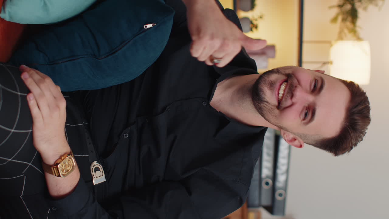 joven feliz mirando con aprobación a la cámara mostrando los pulgares hacia arriba, como un signo positivo, buenas noticias