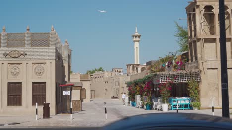 Vista-Del-Minarete-En-El-Distrito-Histórico-De-Al-Fahidi-En-Dubai,-Emiratos-árabes-Unidos-Con-Un-Avión-Volando-En-El-Cielo---Toma-Amplia