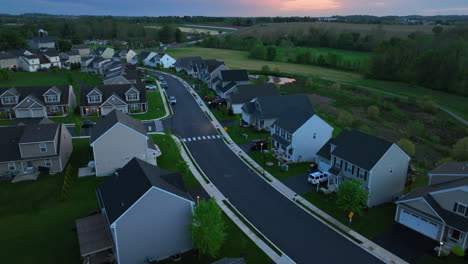 Aerial-pull-back-of-sprawling-American-neighborhood-with-beautiful,-colorful-sunset