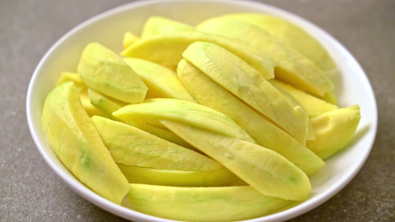 mango verde fresco y dorado en rodajas en un plato