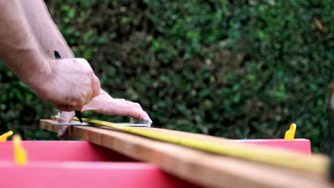 Taking-Measurements-in-Slow-Motion,-Carpenter-Prepares-Wood-for-New-Project,-Daytime-Outdoors