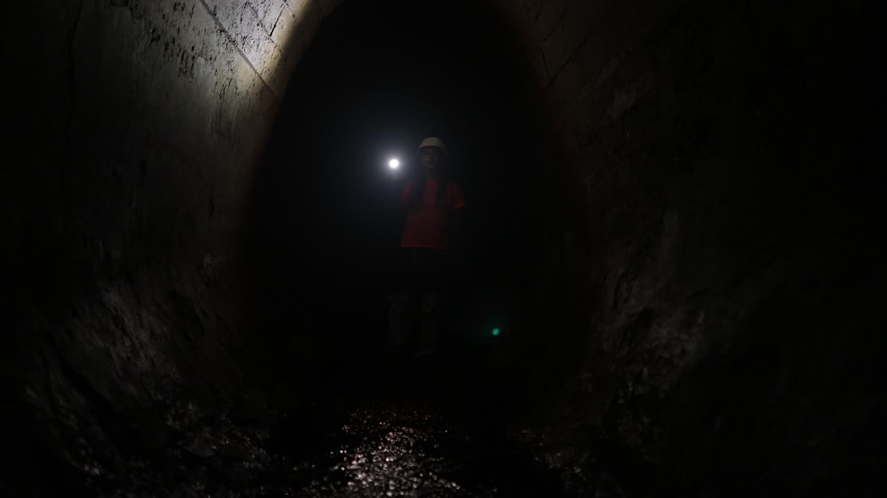 불 을 들고 어두운 터널 을 탐험 하는 사람