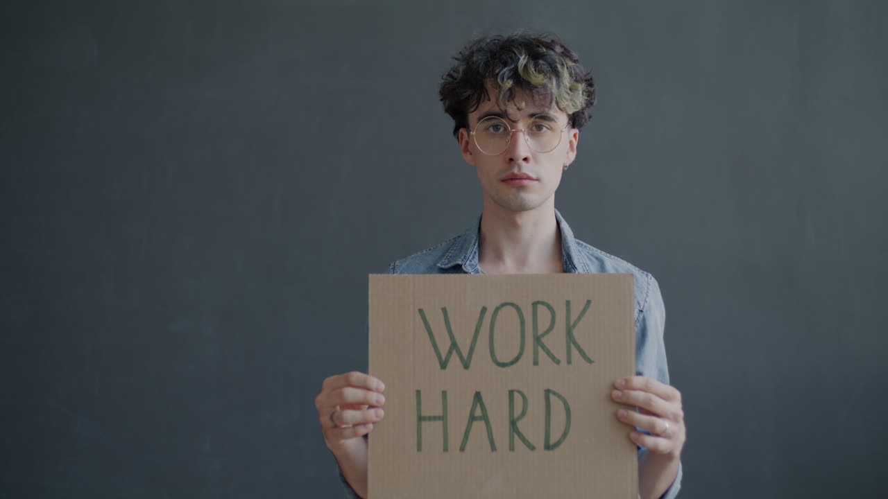 Young Man Holding a Cardboard Sign Reading 'Work Hard'