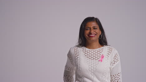 Studio-Portrait-Of-Smiling-Mature-Woman-Wearing-Pink-Breast-Cancer-Awareness-Ribbon-Against-White-Background-4