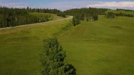 Aerial-view-rising-and-following-a-lone-car-driving-along-a-scenic-country-highway