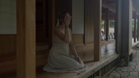 Friedliche-Weibliche-Modellfrau-Mit-Brille-Lächelt-Im-Traditionellen-Japanischen-Hausgarten-In-Okinawa-Japan-Im-Tamaudun-Mausoleum