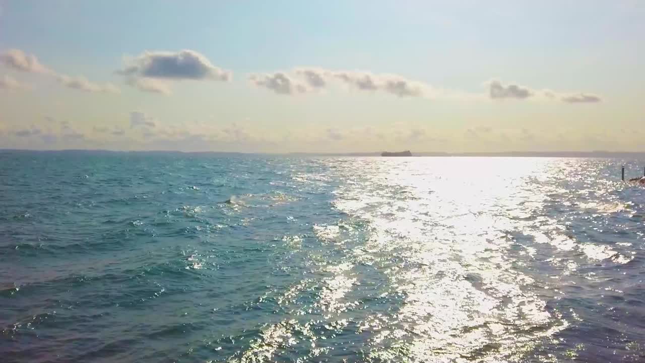 바다 위의 평온한 오후의 풍경, 평화로운 파도와 하늘의 따뜻한 음색은 평온과 자유의 느낌을 만니다.