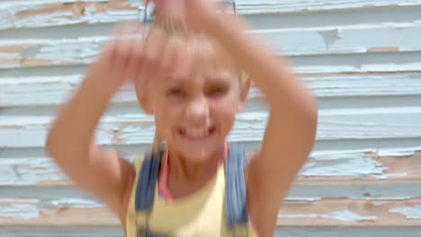 portrait of happy caucasian girl jumping and rising hands over beach house