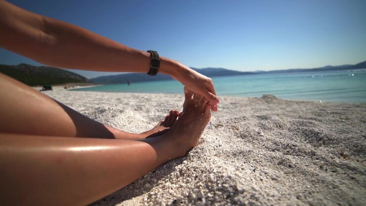 Woman Relaxing on a White Pebble Beach by the Sea