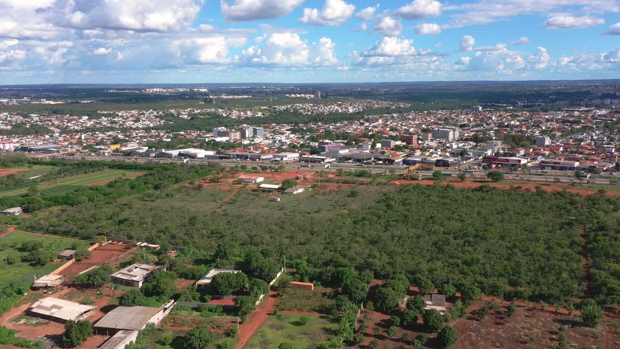La composizione ad alta quota rivela una vasta matrice di vegetazione nativa verde del Cerrado interrotta dall'arteria autostradale con terreno rosso e appezzamenti disboscati sparsi, Brasile