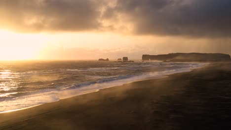 experience the spellbinding aerial views of iceland's black sand beach, where mighty waves meet the sunset's glow