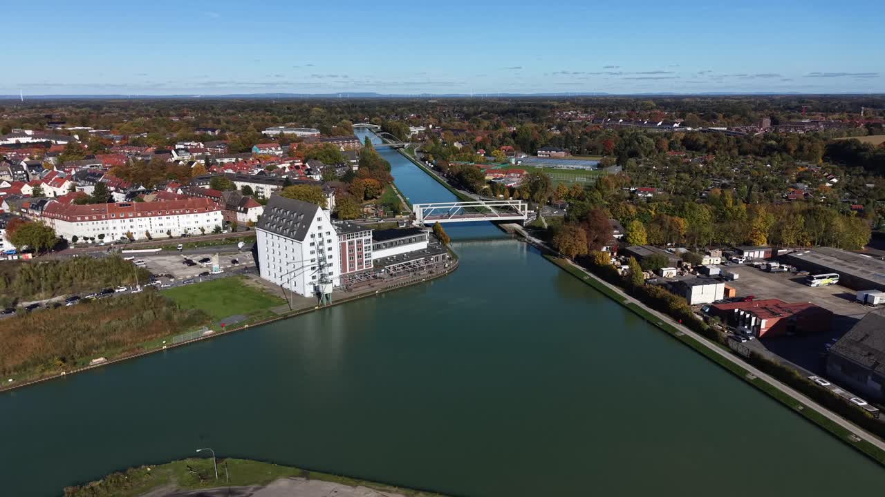 Port pier building with crane at river in German town at sunny day. Aerial wide shot. Sunny day in fall. Bridge with cars and bikes. Suburb neighborhood with colored trees in autumn