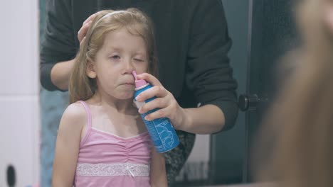 mommy irrigates nose of scared girl at large mirror