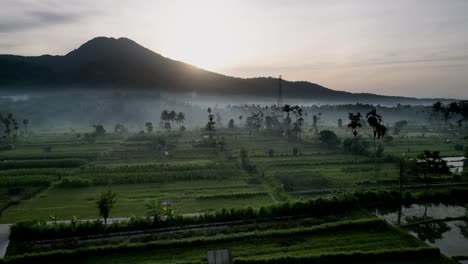 Drone-flying-over-farm-land-showing-a-footpath-leading-into-the-distance-with-mist-and-a-mountain-in-the-background