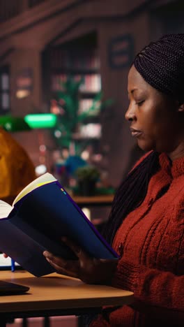 vertical video black female student taking notes surrounded by books and study materials