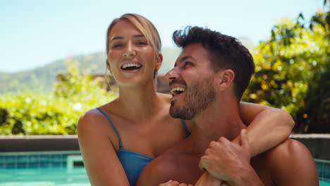 portrait of loving couple on holiday hugging in swimming poo