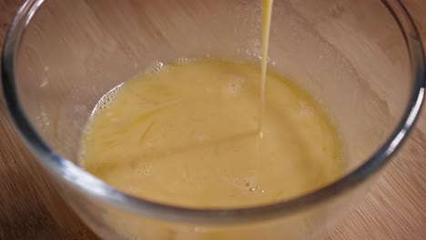 dipping chicken breast fillet into glass bowl with whisked eggs