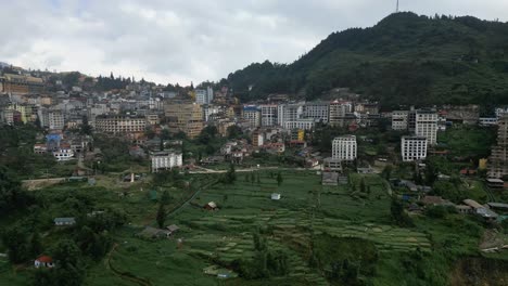 Beautiful-aerial-shot-of-a-city-in-Vietnam-in-the-green-lush-mountains-during-a-overcast-day