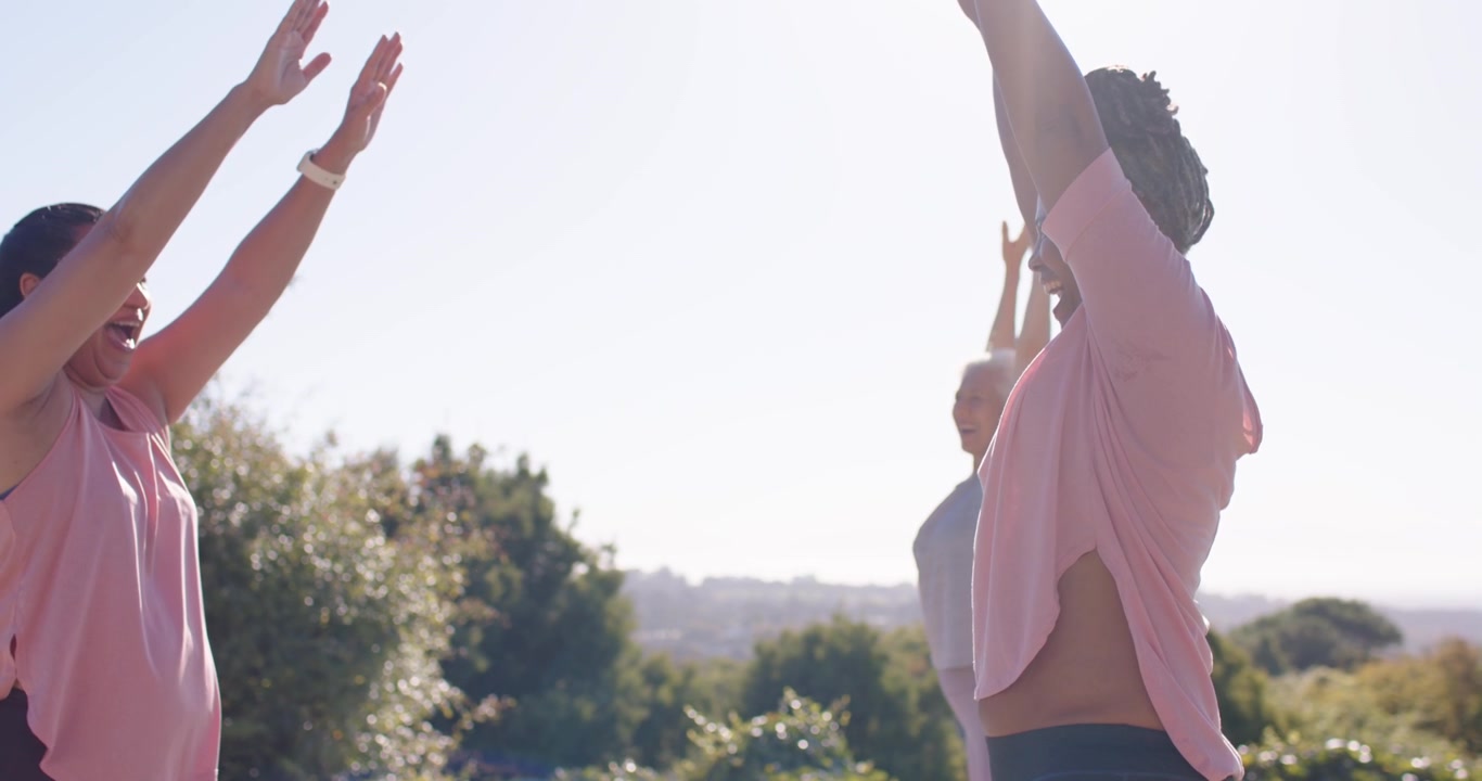Un'anziana e due donne, dopo l'indicazione della lezione, che sollevano e alzano sopra la testa su tappetini verdi per il fitness.