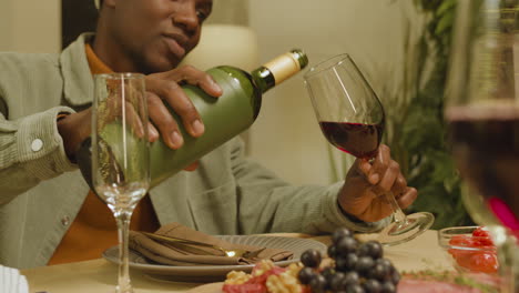 man pouring red wine on his glass