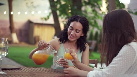 People,-Communication-And-Friendship-Concept-Smiling-Young-European-Women-Drinking-Orange-Juice-And-Talking-At-Outdoor-Cafe