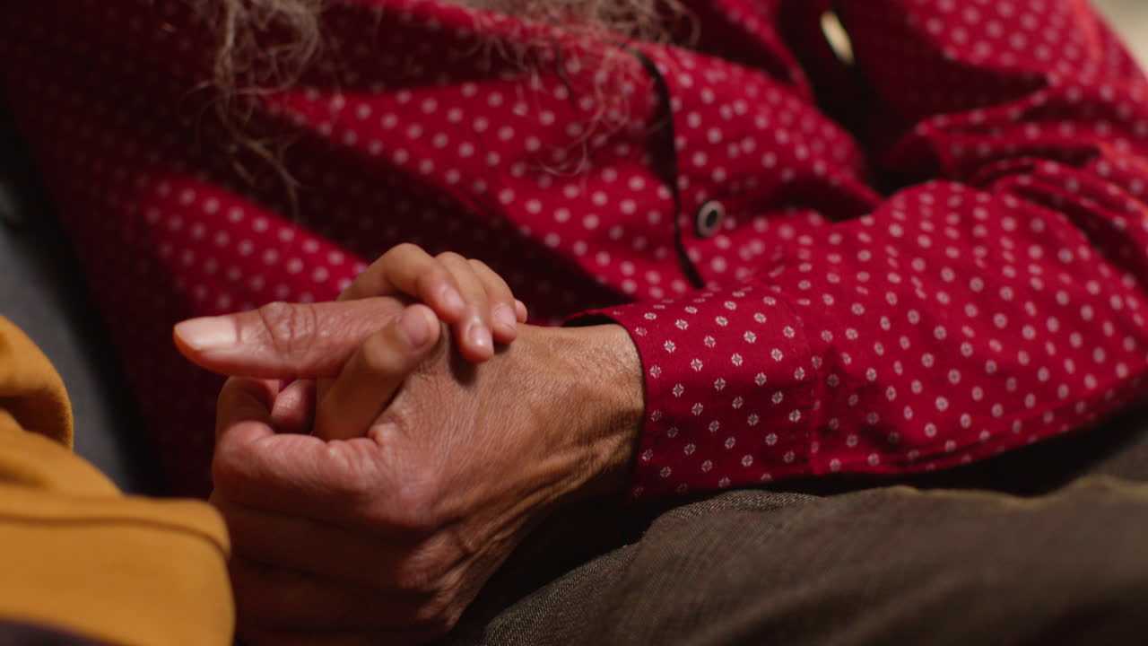 Close Up Of Sikh Grandfather And Grandson Sitting On Sofa At Home Holding Hands Together