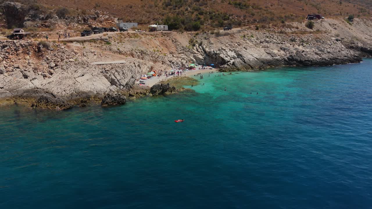 Hidden beach in Albania with a few visitors enjoying clear turquoise waters on a sunny day