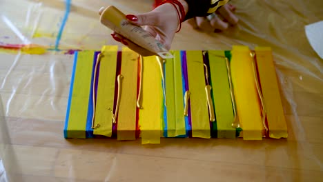 a woman using painters tape to finish her colorful stripes on a canvas
