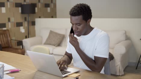 african american startup manager talking on cell phone and writing note