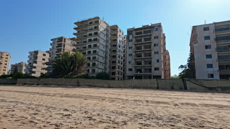 abandoned beachfront high-rise buildings under a clear blue sky with sand in the foreground