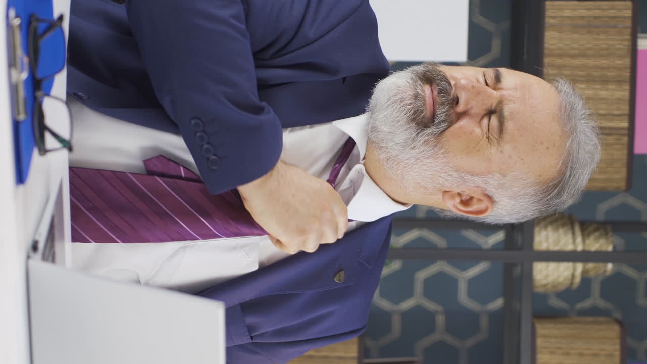 우울하고  ⁇ 은 노인 사업가가  ⁇ 타이를 풀고 있는 수직 비디오입니다.