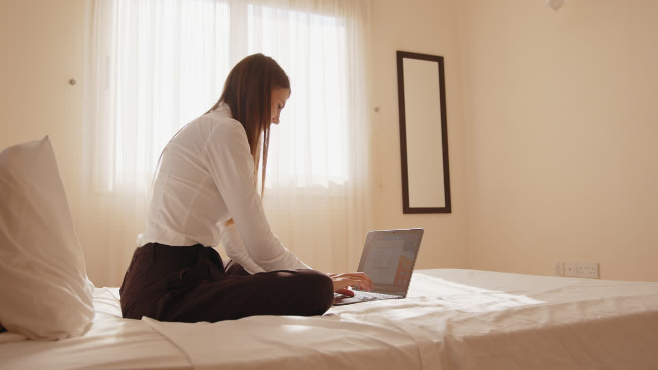 침대에 노트북으로 일하는 여자