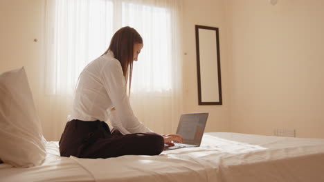 mujer trabajando en una computadora portátil en una cama