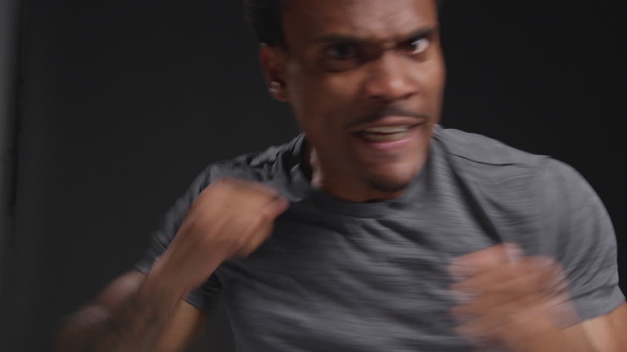 남자 권투 선수가 체육관에서 훈련하고 카메라를 향해 스파링하고 검은 바탕에 맞서 싸우기 위해 준비하는 스튜디오 초상화