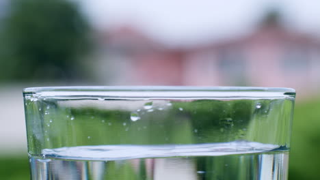 detail of water drops falling inside a glass cup