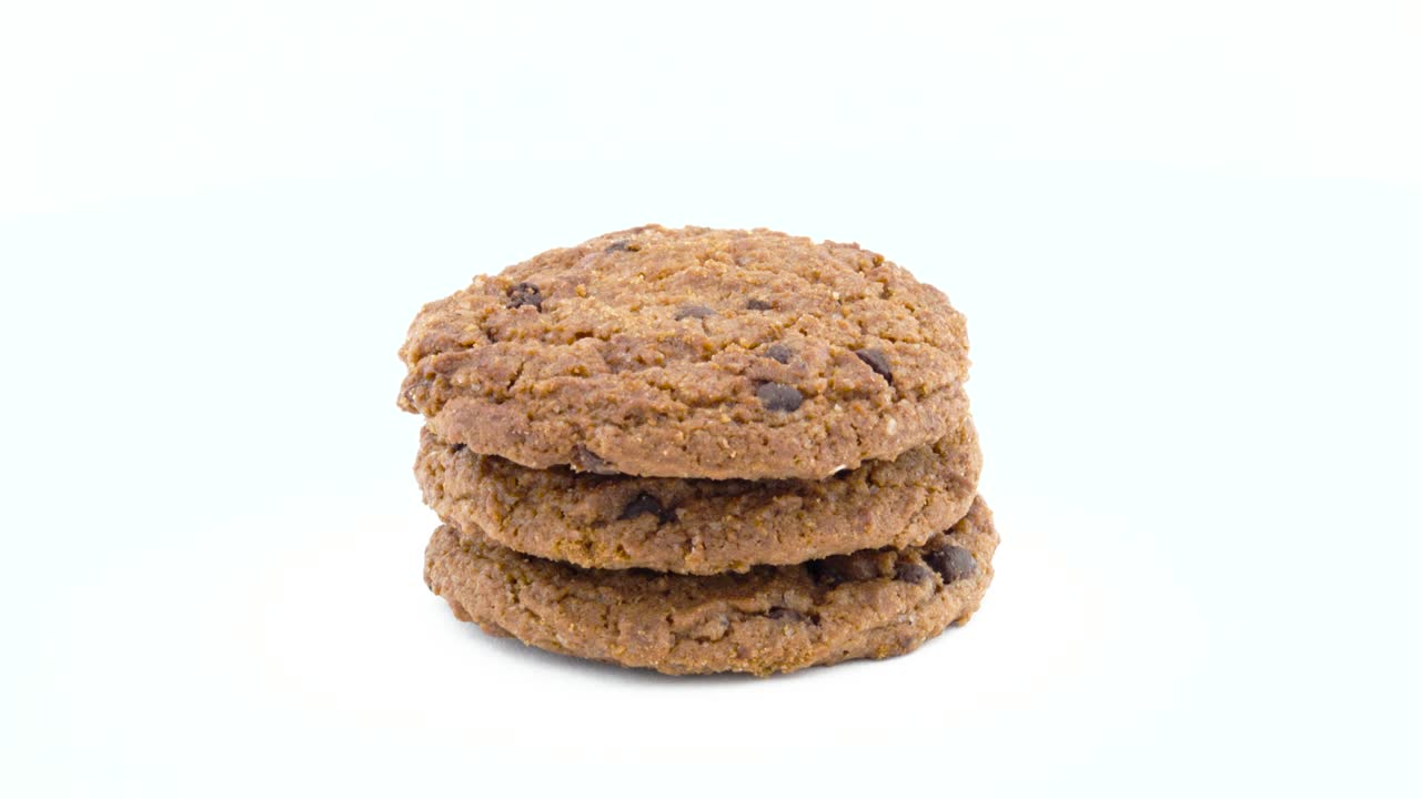 Full frame of a three soft and chewy chocolate chip oatmeal cookies rotating on the turntable. Isolated on the white color background. Close-up. Macro.