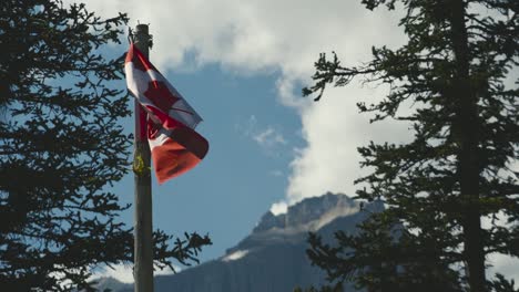 die kanadische flagge gegen den himmel an einem blauen sonnigen tag in den rocky mountains von kanada am moraine lake im banff national park, alberta