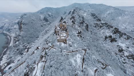 Slow-descending-rotating-aerial-shot-of-ruin-Dürnstein,-Wachau,-during-a-snowy-Winter-day