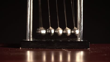 Newton's-cradle-over-black-background-FRONT-VIEW-CLOSE-SHOT