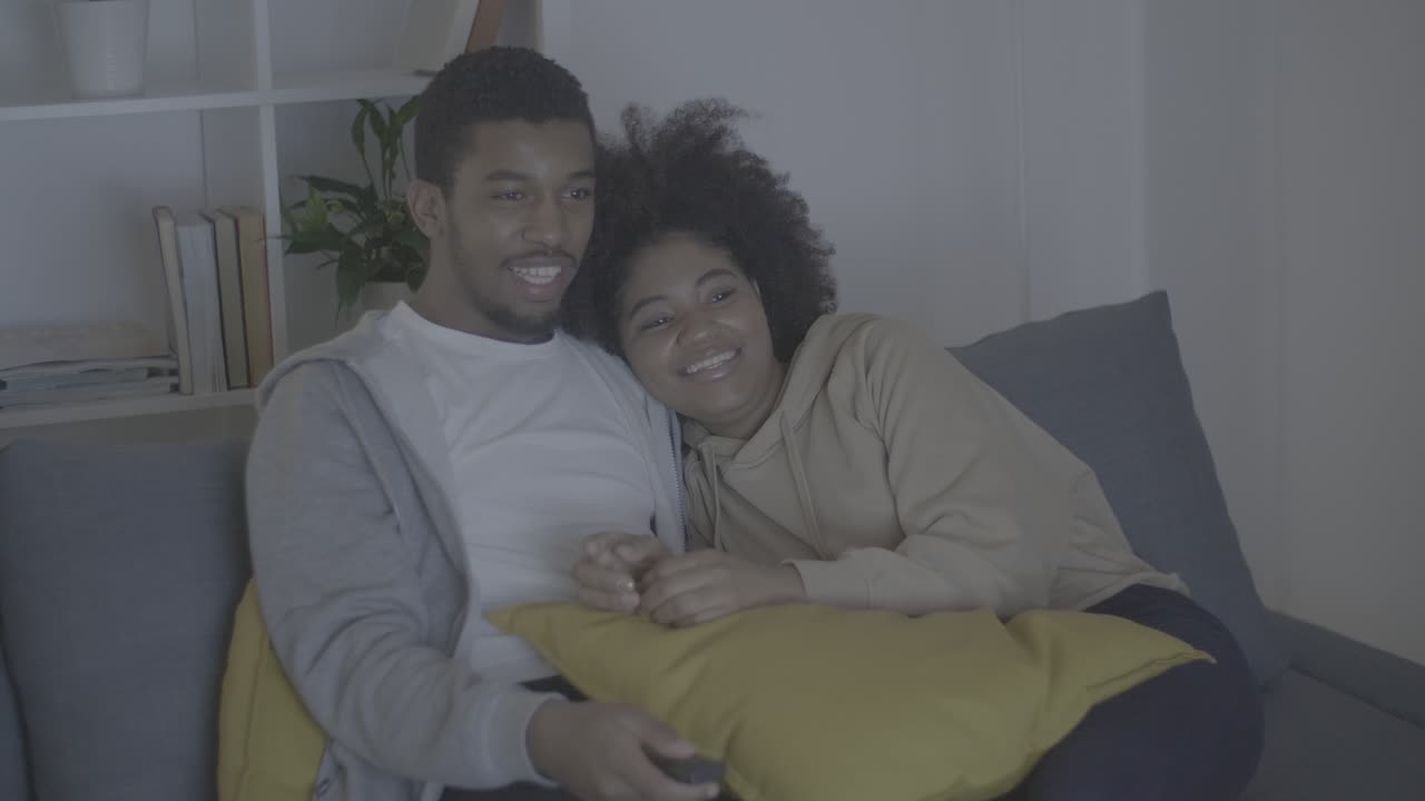 Young african american couple having fun while watching TV in the dark