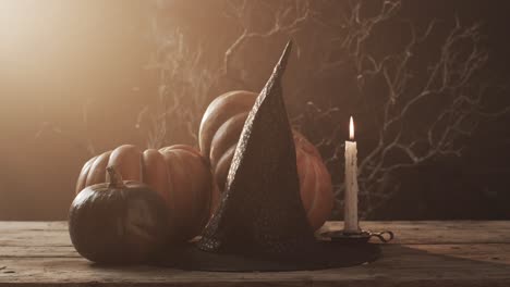 video of halloween pumpkins, hat, candle and copy space on brown background